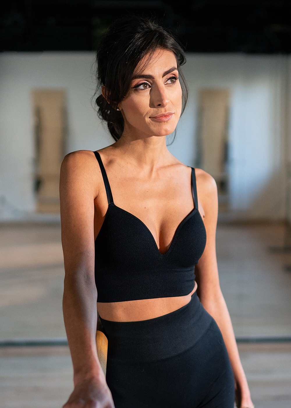 Woman in black activewear studio setting.